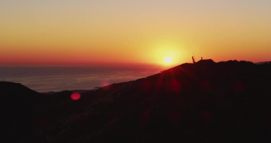 The sun sets over the horizon and mountains are silhouetted