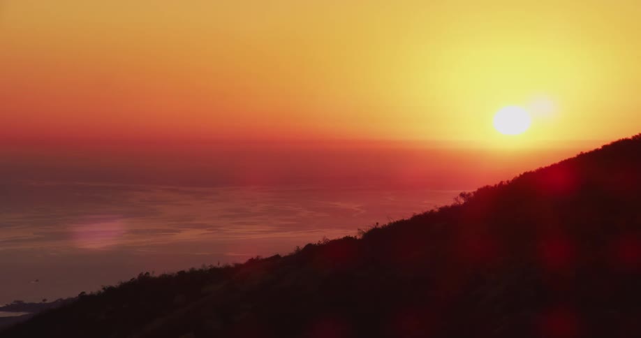 The sun is flaring over the mountain