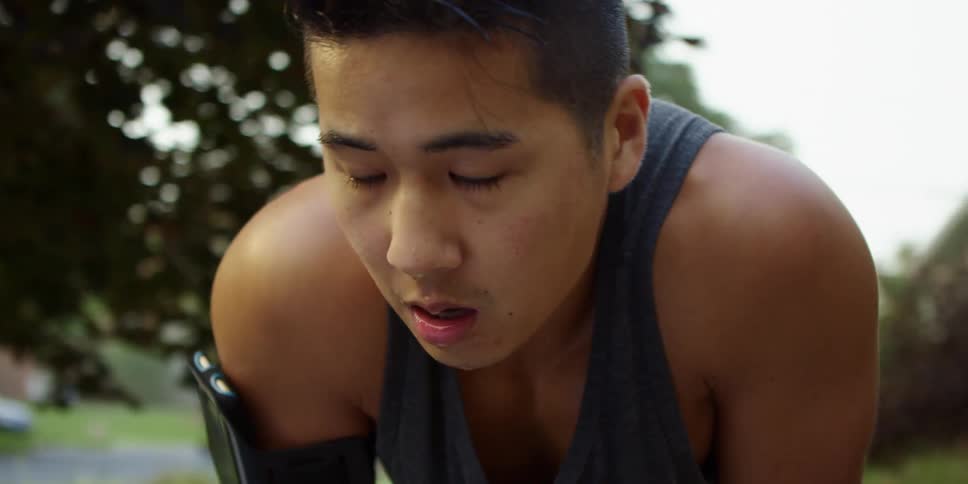 Asian tired man with his hands on knees breathing in and out