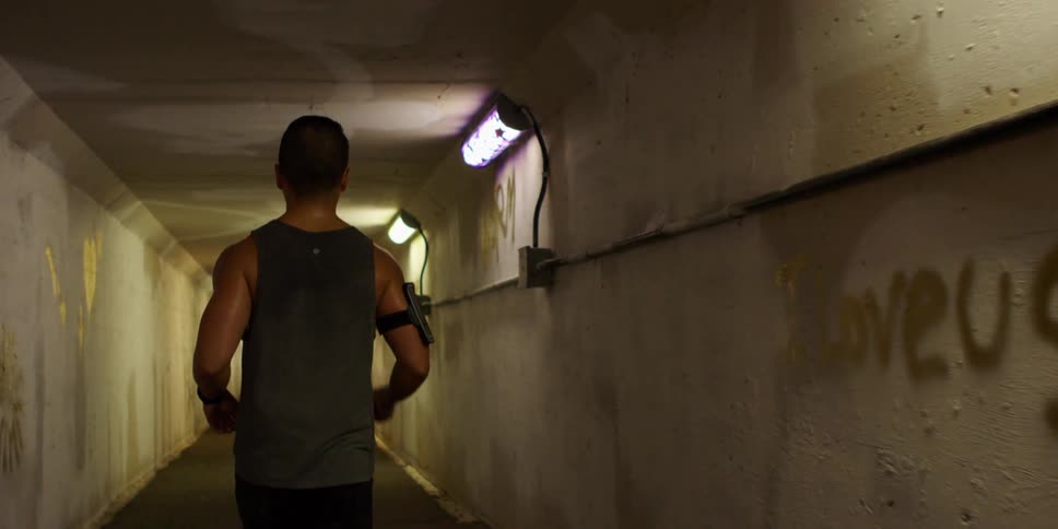 A man is jogging through a tunnel