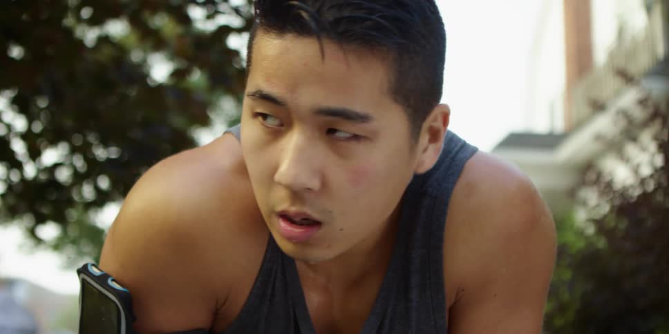 A young man dripping in sweat bends down to catch his breath