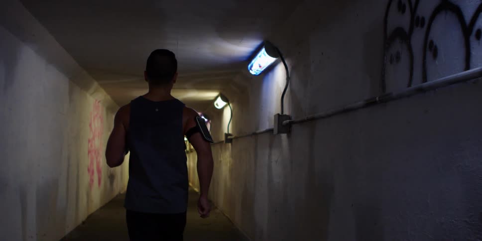 A man jogs down a narrow tunnel