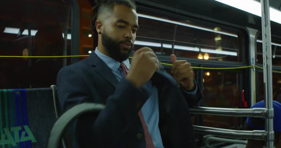 A man sits down on the bus and uses his cell phone