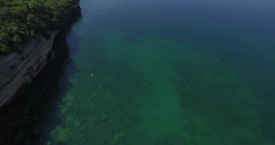 Two kayaks float on clear, green water