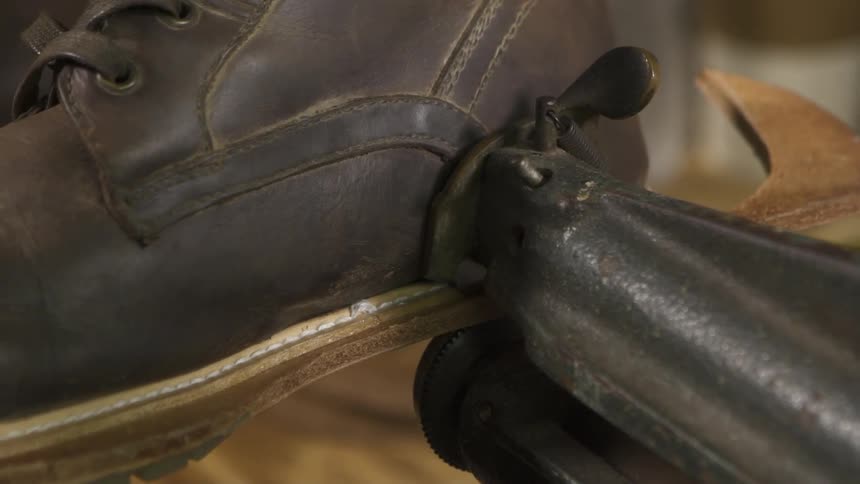 A boot sole is being secured with a tool
