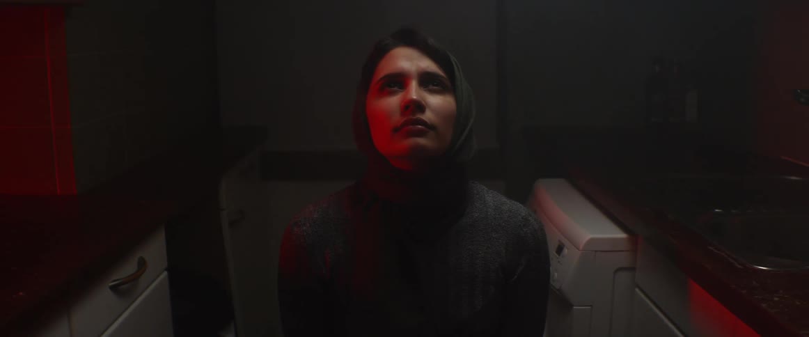 A woman sits at home and looks up at the ceiling and closes her eyes