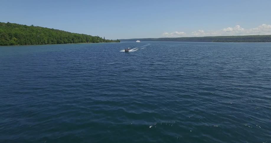 A boat is traveling over a body of water on a sunny day