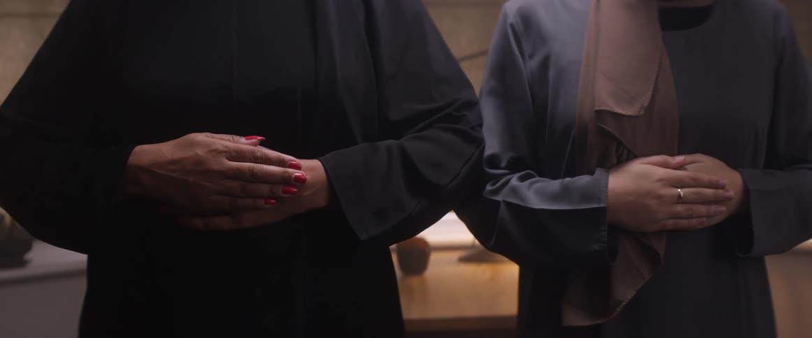 Two women with headscarves perform the ritual prayers of islam