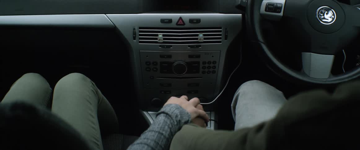 Woman places her hand over the hand of a man touching a gear shift inside a car