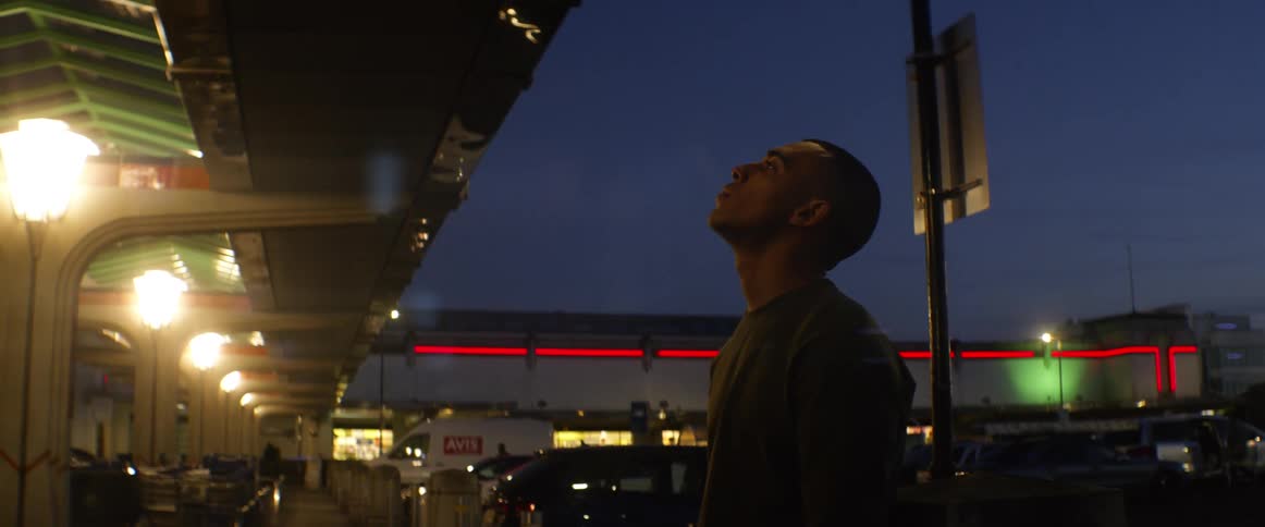 A man standing in a parking lot at night smoking
