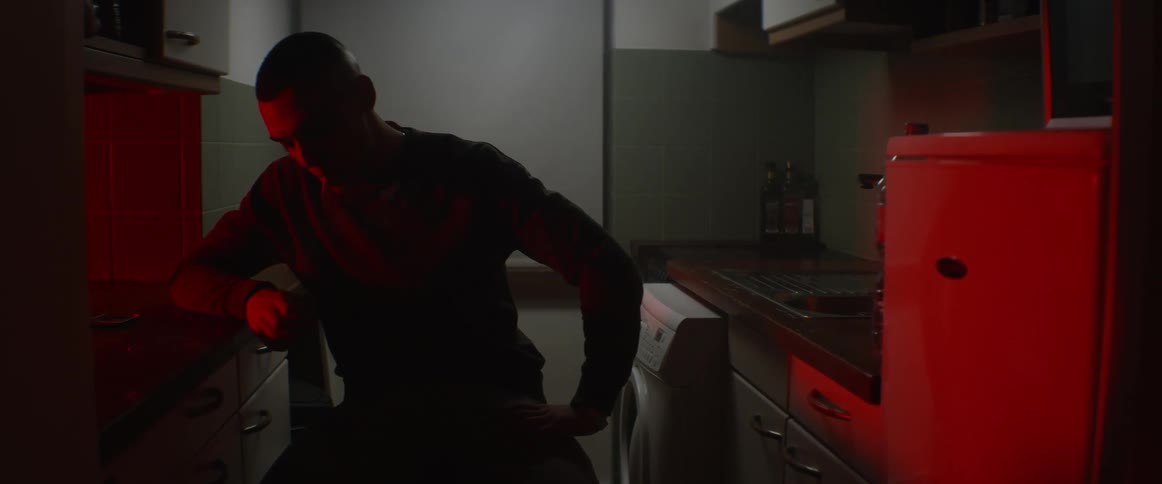 A young man sits in his kitchen and smokes