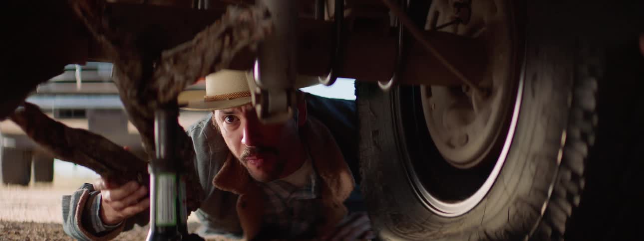 Two men with a jack working on a vehicle