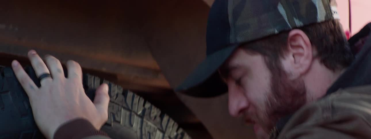 A man with a tool changing a tire on a vehicle