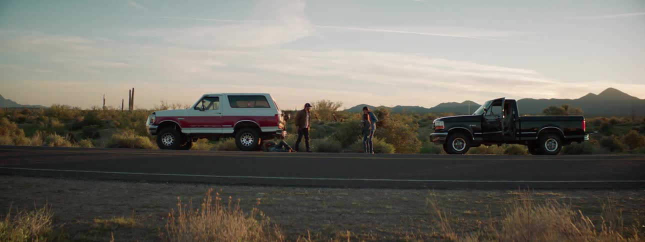 Two cars are parked on the side of the road in a rural area
