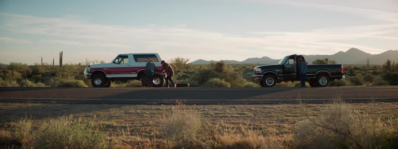 Two vehicles are parked on a road in a rural area