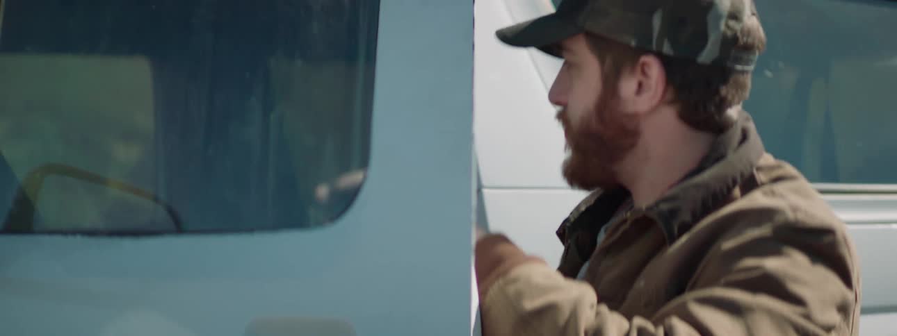 A man walks to his truck and opens the door and grabs something out and closes the door