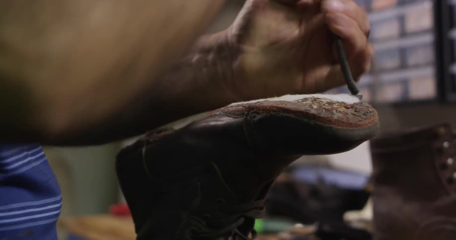 A man peels a sole from a boot in a workshop