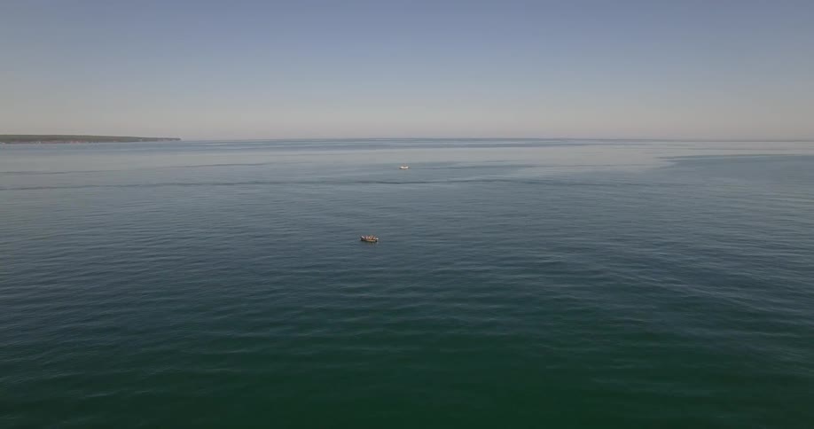 Two boats are in the water below on a sunny day