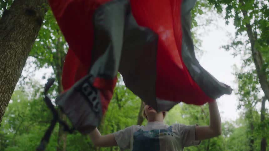 A girl is setting up a tent in the forest