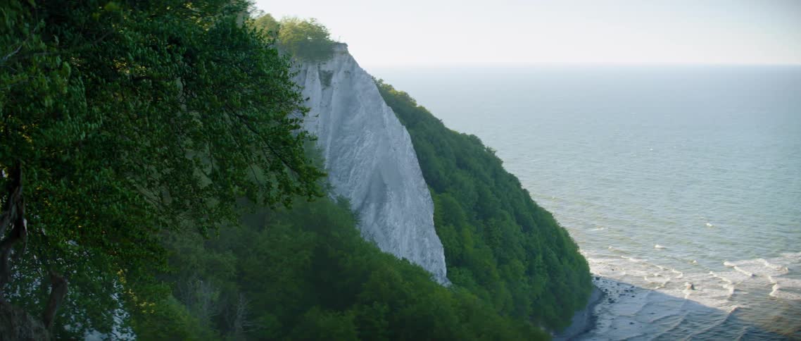 An aerial view of a mountain is displayed near an ocean