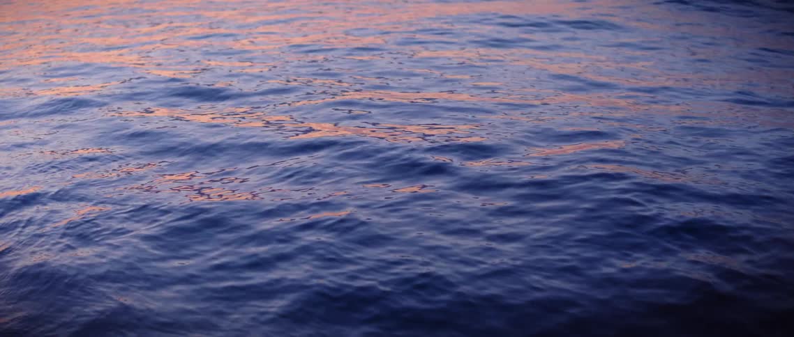 Gentle waves on the ocean reflect the orange sky