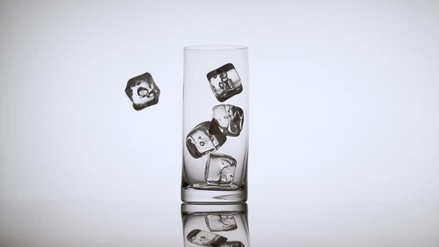 Several ice cubes fall into a glass