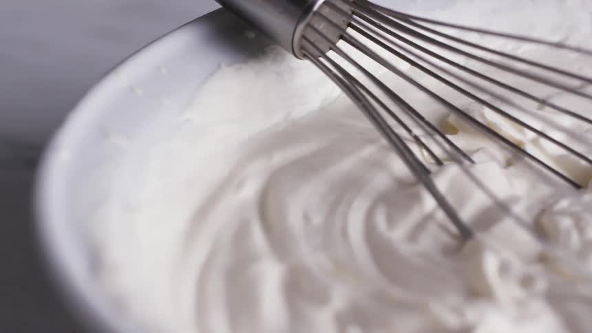 A bowl of whipped cream with a whisk