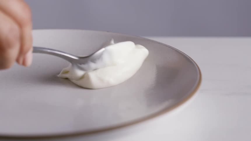 A person puts cream on a plate