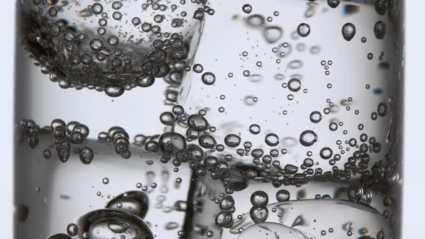 Bubbles rising in a drinking glass filled with ice