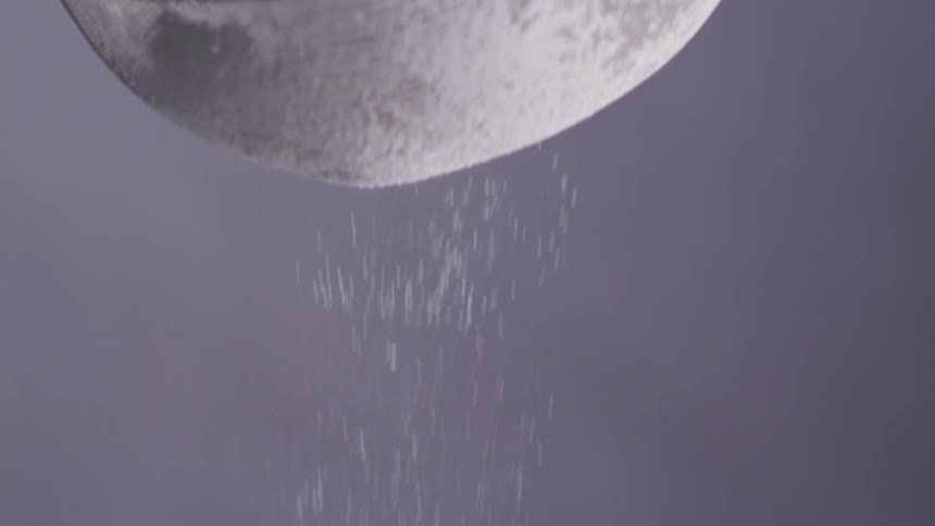 A white powder being sifted through a metal sieve