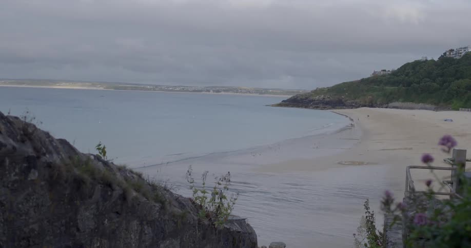 Waves lap gently against the beach on a cloudy day