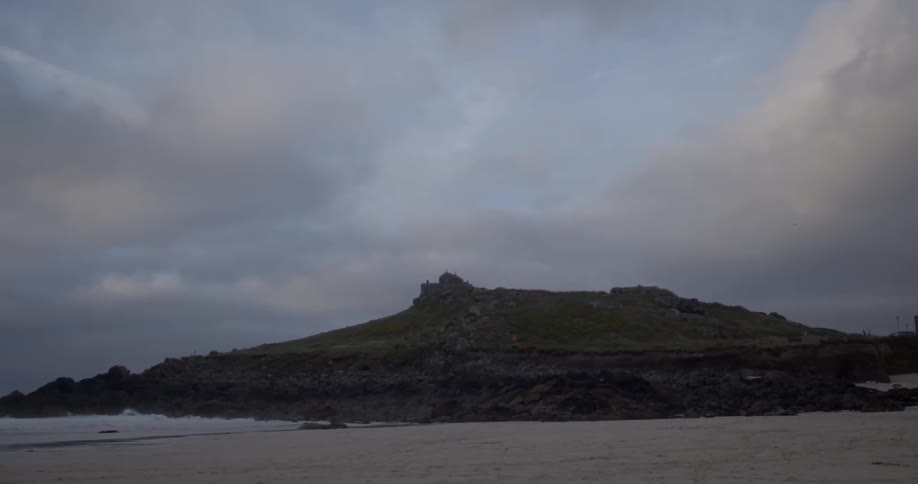 A green mountain sits under a cloudy sky