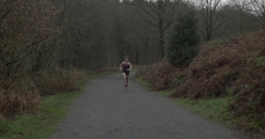A woman running down a tree lined road
