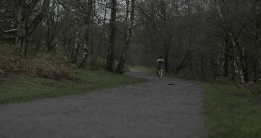 A woman runs down a path in the woods