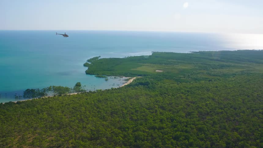 A helicopter flying over the shoreline