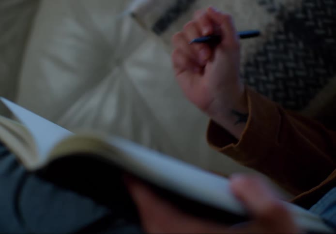 A person is writing in their notebook on the couch