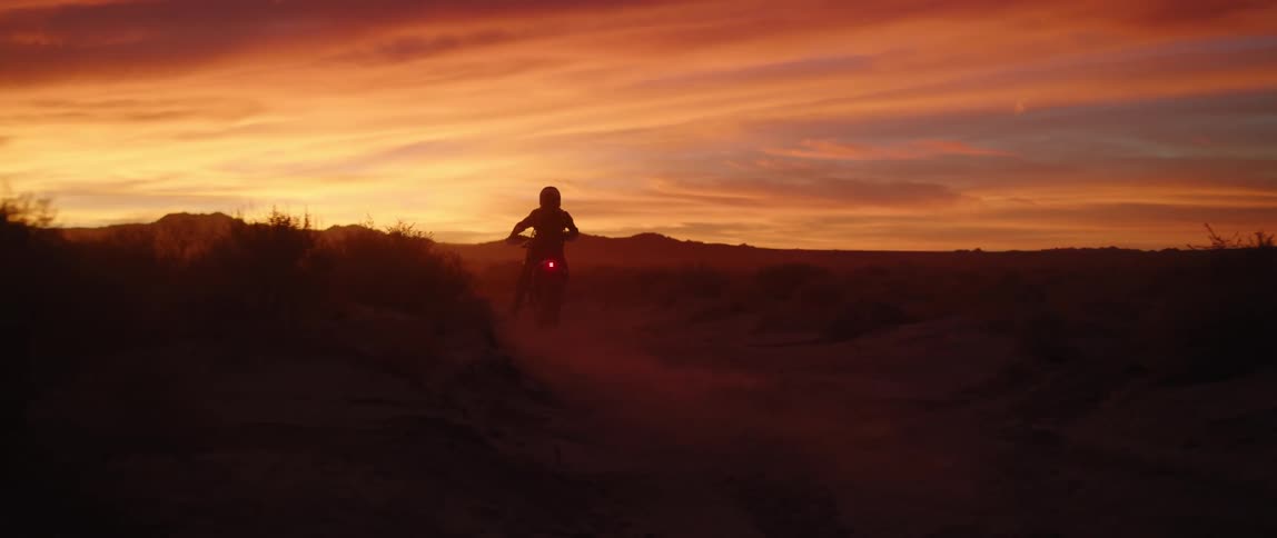 A person riding on their motorbike in the wilderness at sunset