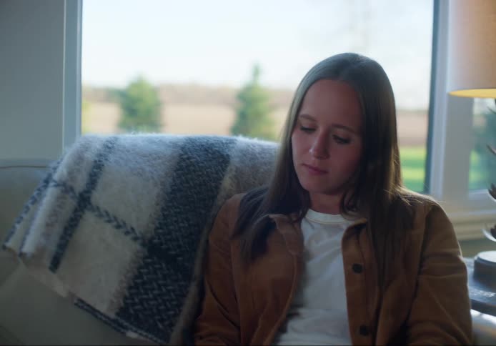 Female sitting on sofa with her legs propped up while she uses a pen to write in her journal