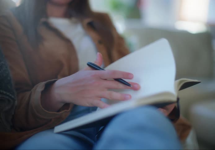 A woman sits and writes in a book