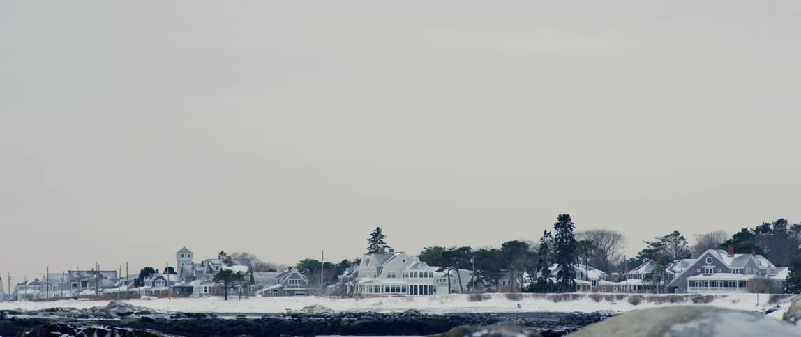 The sun sets on a small coastal village in New England covered in snow