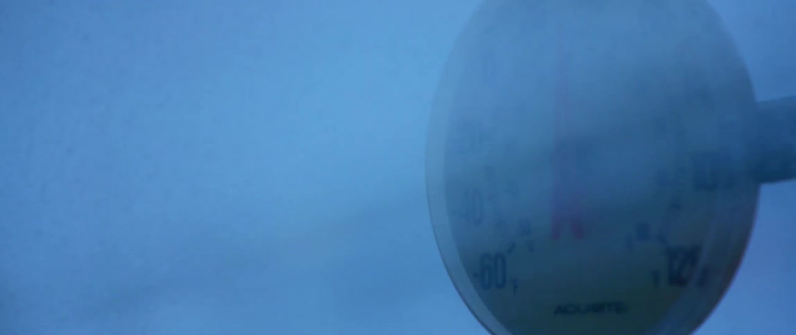 A temperature gauge sits outside during a winter storm