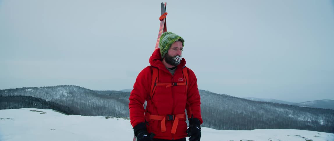 An outdoorsman stops along the ridge of a snowy mountain range on a freezing winter day
