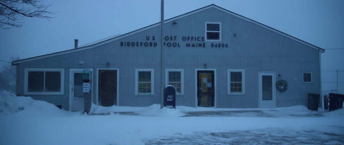 Snow drifts against a small post office in Maine during a blizzard