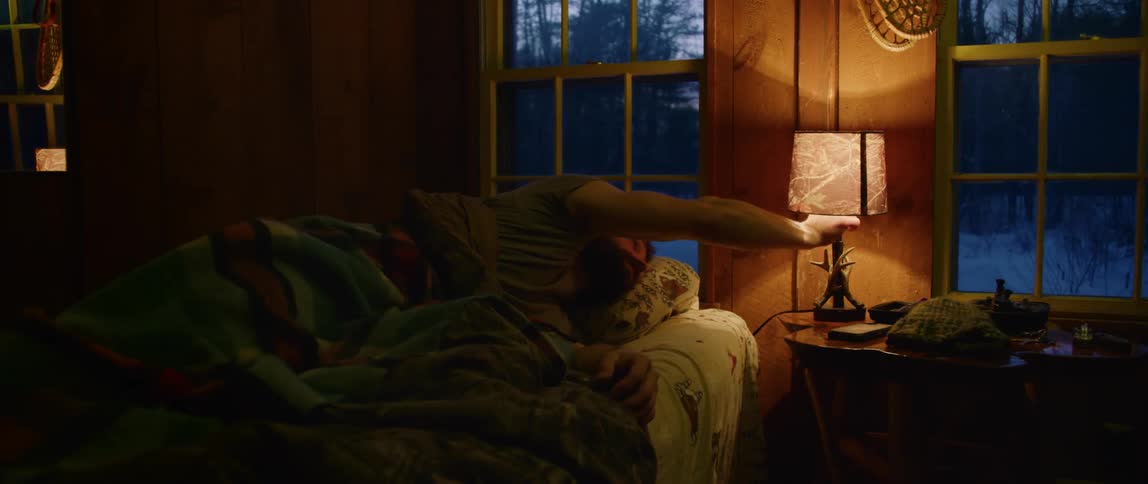 A man rolls over on an early winter morning and turns on a lamp