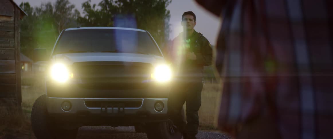A male police officer gets out of his truck on a rural property
