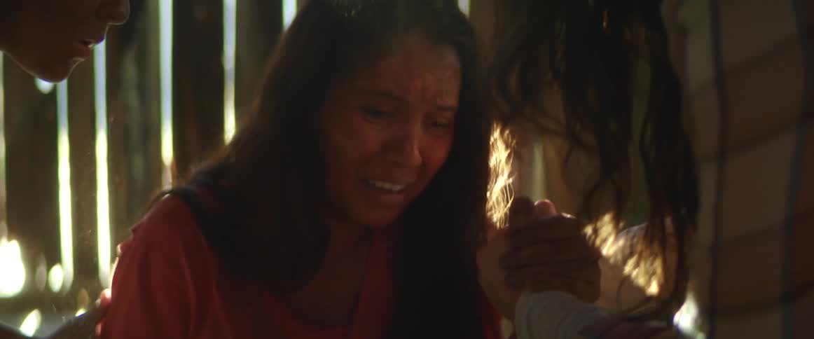 Two people help a woman who is crying down to the ground