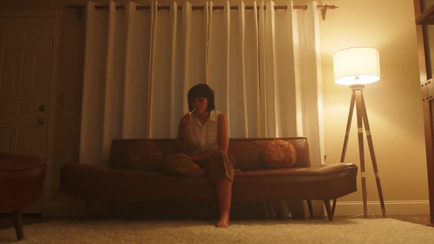 A woman sits at home and smokes