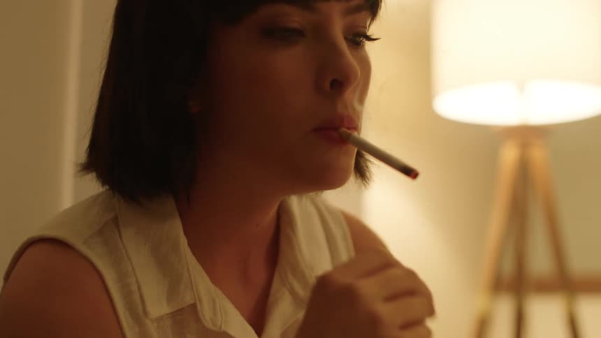Woman lights a cigarette then removes the cigarette from her mouth