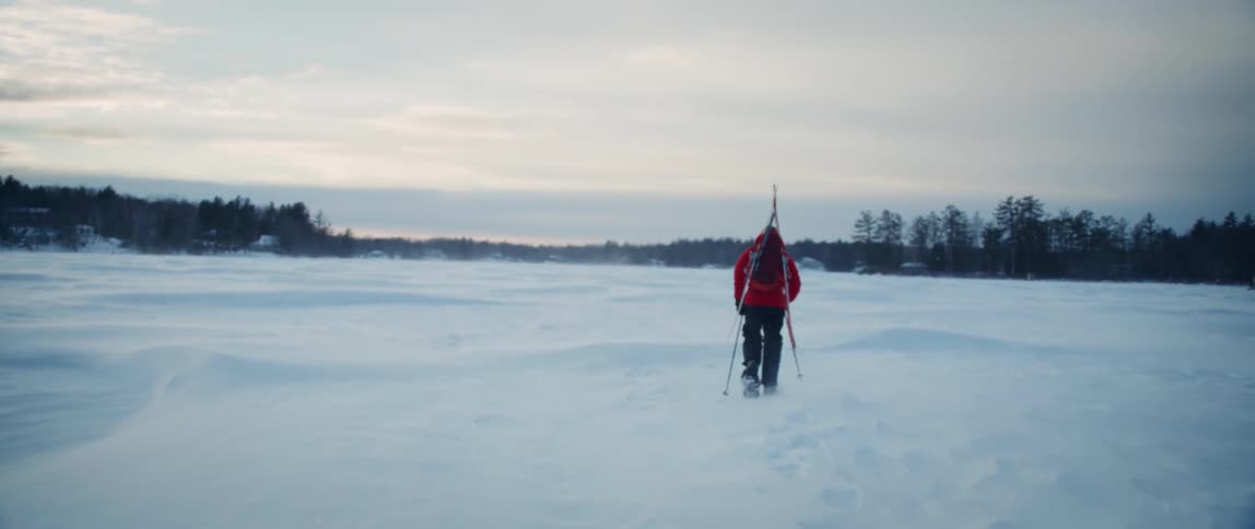 An outdoorsman sets out across a frozen lake in the dead of winter