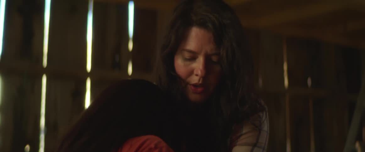 Woman assists another woman in sitting down in a barn